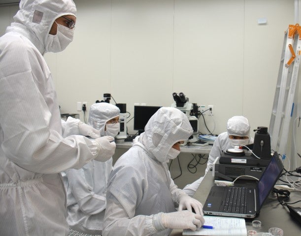 Researchers at OIST measuring a thin film's conductivity in a cleanroom